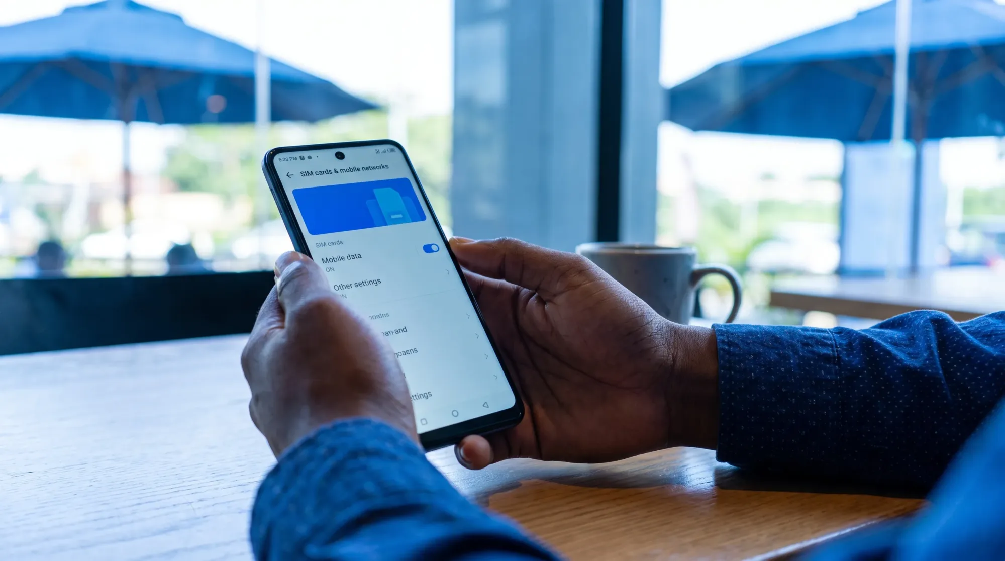 A Nigerian smartphone user at a table checks mobile network settings on an Infinix Hot 20 5G with the screen facing them and no private details visible.