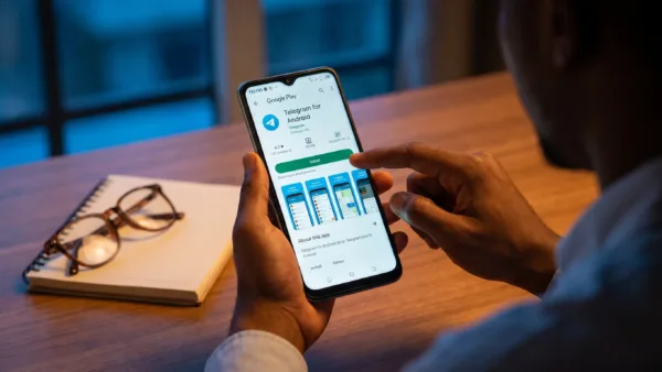 Hands use a TECNO phone on the Telegram Android page to start a safe download.