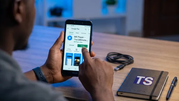 Hands use a Tecno phone to open the MX Player page in Google Play and start the download.